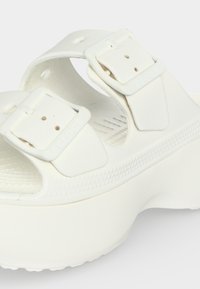 Sandale à plateforme blanche avec deux brides réglables à boucle et semelle intérieure texturée sur une semelle épaisse.