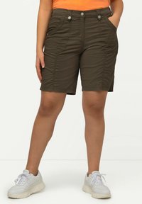 Pantaloni corti verde oliva realizzati in tessuto morbido, con tasche frontali, dettagli cuciti e due bottoni decorativi in vita.