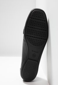 Semelle de chaussure en cuir noir avec caoutchouc texturé pour l'adhérence, présentant des trous de ventilation circulaires. Comprend la marque "GEOX" et les détails du brevet.