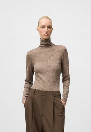 Maglione a collo alto marrone in tessuto a coste abbinato a pantaloni brown a vita alta e gamba larga, con tasche laterali.