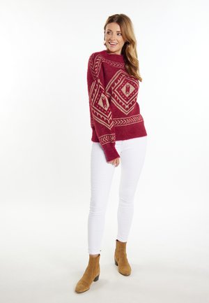 Bordeaux strikket sweater med et geometrisk mønster i creme, høj hals og løs pasform. Sammen med hvide skinny jeans og brune ankelstøvler.