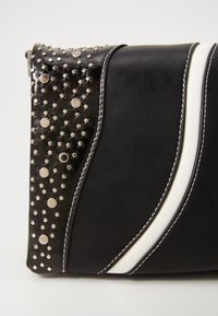 Clutch nera in ecopelle con borchie argento, strisce bianche a contrasto e cuciture decorative. Presenta una texture lucida e una forma strutturata.