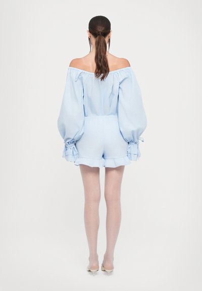 Rompers bleu clair dénudé d'épaules avec des manches bouffantes, ceinture élastique et ourlet volanté. Tissu lisse à texture douce, longueur au-dessus du genou.