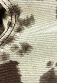 Katoenen stof met een beige basis en donkerbruine vlekken in een camouflagepatroon. Zichtbare textuur van het geweven materiaal.