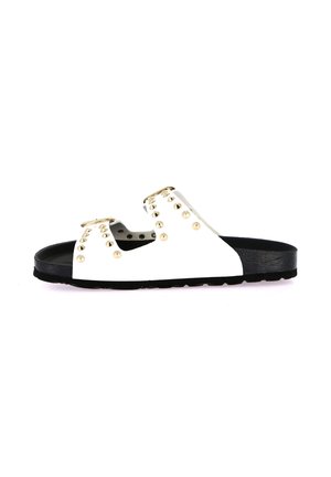 Sandalo bianco slip-on con due fasce borchiate, fibbie dorate e suola nera sagomata, visto di lato su sfondo bianco.