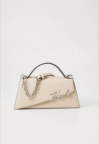 Beige läderhandväska med triangulär form, handtag upptill, silverkedjeskedja och en logotyp i metal med kursiv stil.