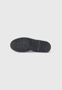 Black rubber outsole with deep lug patterns for traction. Features a flat, solid design with reinforced heel and midsole.
