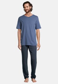 Mäns lounge-set bestående av en blå kortärmad T-shirt med V-ringning och mörka byxor, båda i mjukt tyg med avslappnad passform och utan mönster.