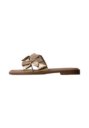 Sandale plate marron avec bride métallique dorée et multiples pétales décoratifs sur le dessus, sur fond blanc.