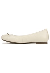 Beige leren ballerina met een ronde neus, subtiele plooien en een klein metallic accent op de wreef. Plat zoolontwerp.