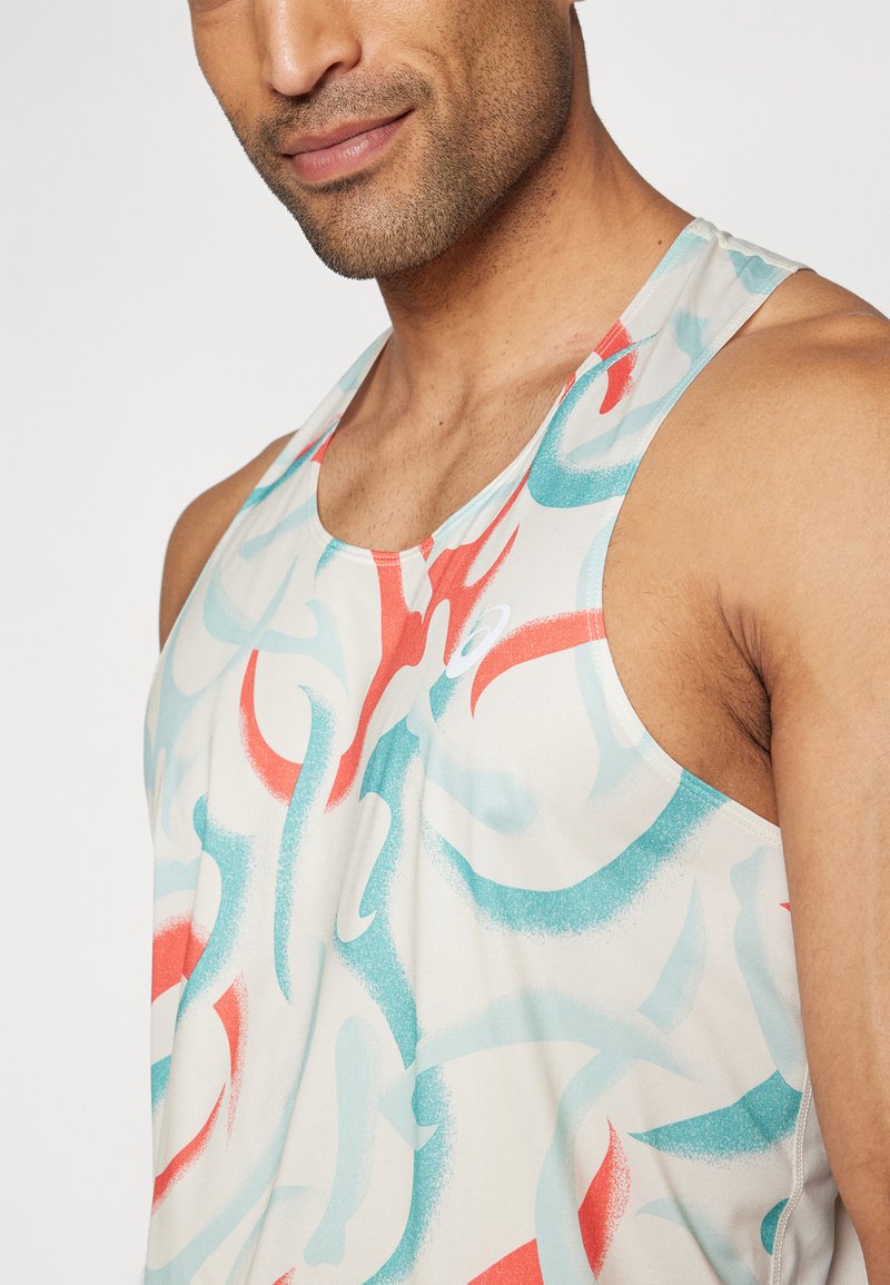 Top ligero sin mangas con base crema, que presenta patrones abstractos en rojo y turquesa en espirales. Diseño deportivo con escote redondo.