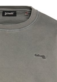 Grå bomulds sweater med ribbede strukturer, rund hals og broderet "Schott" logo på brystet. Har et mærke med størrelsen "L."