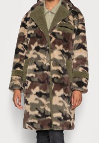 Kurtka kamuflażowa z futerka sztucznego, z mieszanką ziemistych odcieni, dużymi klapami i przednią kieszenią na zamek. Miękka w dotyku, luźny krój.