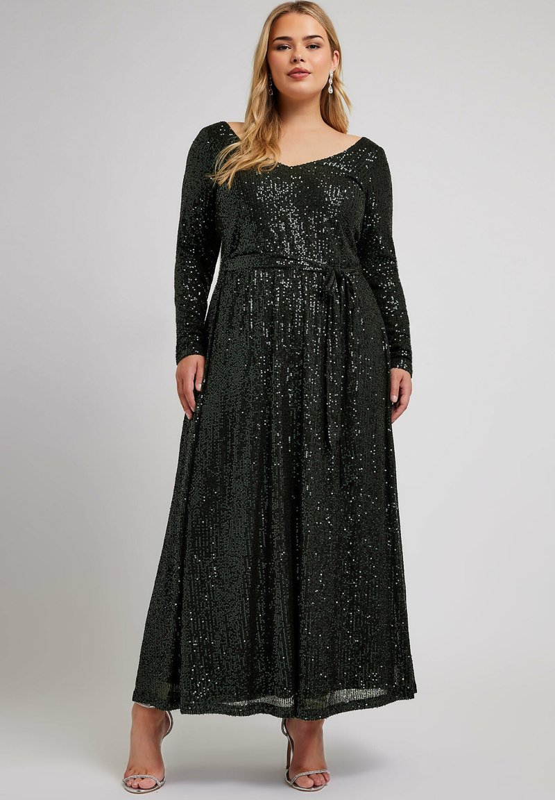 Largo vestido negro de lentejuelas con mangas largas, escote en V y cintura ceñida. Presenta una falda fluida y un cinturón a juego, creando una silueta elegante.