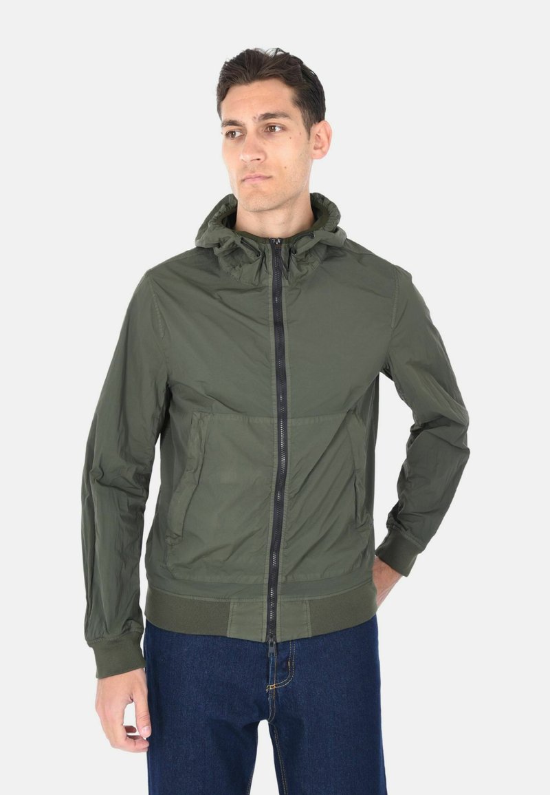 Giacca leggera con cappuccio color verde oliva, chiusura frontale con zip, tasche laterali, polsini e orlo a costine, texture liscia, design casual.