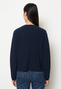 Dunkelblauer Strickpullover mit Rundhalsausschnitt, gerippter Textur und langen Ärmeln. Der Saum ist leicht verkürzt und das Design ist einfach und klassisch.