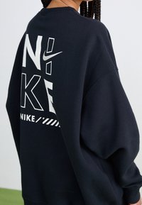 Mörkblå oversized sweatshirt med vit Nike-logga och text på baksidan. Mjuk tyg med rundad halsringning och sänkta axlar.