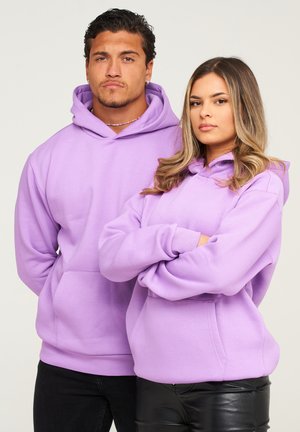 Lavendel-Hoodies aus weichem Stoff, versehen mit großen Fronttaschen und Kordelzügen an der Kapuze, getragen von zwei Personen mit verschränkten Armen.