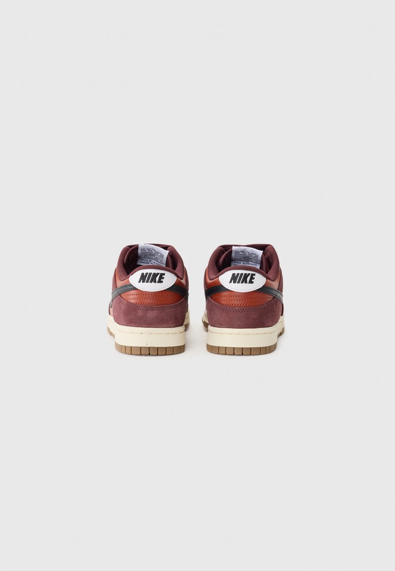 Baskets Nike Dunk en suède marron avec des accents en cuir, dotées d'un semelle intermédiaire crème et d'une semelle extérieure en caoutchouc marron, ainsi qu'un détail de logo blanc sur le talon.