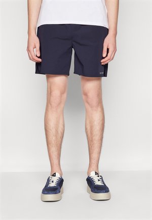 Pantaloni da bagno blu navy realizzati in tessuto leggero, con un design semplice, vestibilità standard e un piccolo logo sul lato.