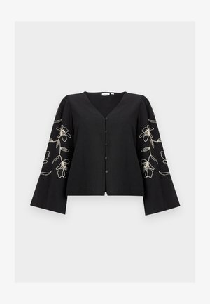 Blouse noire à manches longues boutonnée avec col en V et broderie florale blanche sur les manches larges légèrement bouffantes.