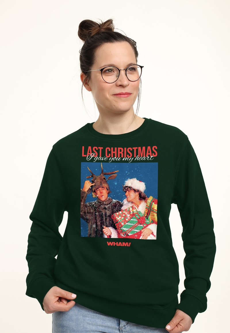 Felpa verde scuro con una grafica frontale di due figure in abbigliamento invernale, con il testo "LAST CHRISTMAS" e "WHAM!" in rosso audace.