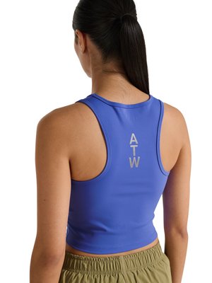 Frau mit dunkelbraunem Pferdeschwanz, die ein ärmelloses blaues kurz geschnittenes Tanktop trägt, auf dessen Rücken "ATW" vertikal aufgedruckt ist.