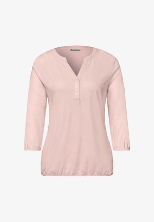 Blouse rose clair à manches longues avec trois boutons sur le devant, encolure ronde avec une fente en forme de V, poignets et ourlet élastiques.