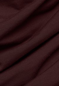 Burgundy pamut szövet, sima textúrával, bordázott mintával és lágy redőkkel, amelyek hangsúlyozzák a puhaságát és esését.