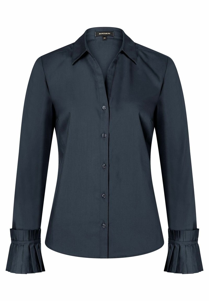 Chemise bleu marine foncé à manches longues avec boutons, col pointu et détails plissés sur les poignets des deux manches.