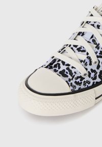Svart og hvit leopardmønstret kanvas sneaker med rund tå, hvite snørebånd og en teksturert gummisåle med svart kant.