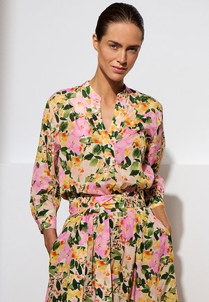 Robe fleurie avec des motifs roses, jaunes et verts. Tissu léger, manches longues, décolleté en V et taille cintrée. Jupe plissée.