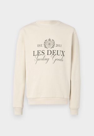 Cream sweatshirt with a rounded neck. Features "LES DEUX Sporting Goods" in dark gray, surrounded by a circular emblem and laurel design.