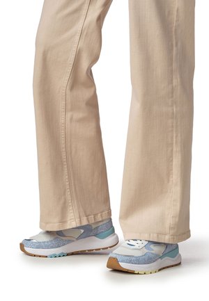 Baskets bleu clair avec des motifs texturés, des accents blancs et des semelles en caoutchouc marron, associées à un pantalon beige clair à jambes larges.