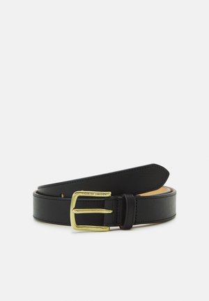 Ceinture en cuir noir roulée avec une boucle en métal doré gravée de "Tiger of Sweden" sur fond blanc.
