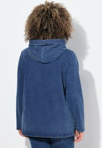 Felpa in denim blu scuro, con cappuccio regolabile e maniche lunghe, dal taglio morbido e una vestibilità rilassata.