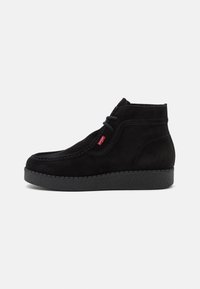 Bottines en daim noir à bout rond, avec un design à lacets, des surpiqûres contrastantes et une semelle extérieure en caoutchouc noir texturée.