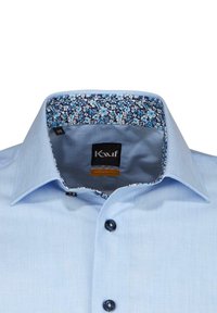 Helle blaue Hemdbluse mit floral gemustertem Kragenfutter, Knopfverschluss und weicher Textur. Etikett besagt "Kauf Modern Fit."