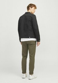 Jachetă din denim negru, croi obișnuit, cu guler ascuțit și manșete cu nasturi. Pantaloni de culoare verde măsliniu, cu tiv la gleznă, asortați cu adidași albi.