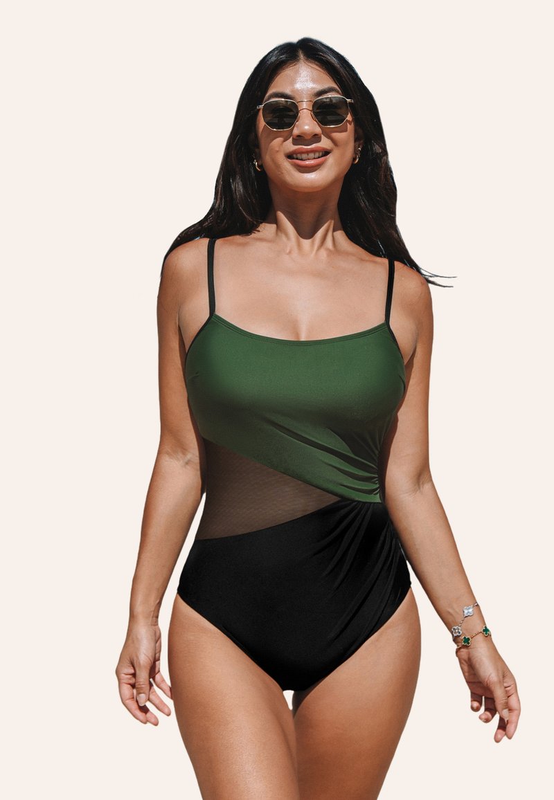 Maillot de bain une pièce avec un haut vert et un bas noir, présentant des détails en mesh et des bretelles ajustables. Texture lisse avec une silhouette ajustée.