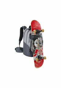 Zaino grigio con spalline imbottite; una tavola da skateboard rossa attaccata, con un design grafico, ruote nere e segni di usura visibili.