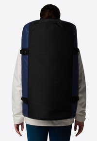 Zaino rettangolare grande in nero e blu navy, realizzato in tessuto resistente. Presenta spallacci regolabili e un design elegante e minimalista.