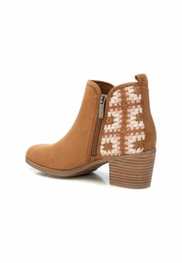 Botas de tobillo de ante marrón con cremallera lateral, acentos de croché texturizado en rosa y marrón, y un tacón apilado con rayas horizontales.