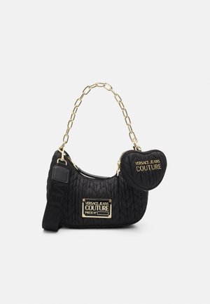 Black quilted shoulder bag with gold chain strap, attached heart-shaped coin pouch, and gold "Versace Jeans Couture" logos.