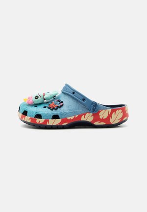 Niebieski chodak z czerwoną podeszwą z beżowymi wzorami liści, ozdobiony zawieszkami z postaciami z kreskówek oraz pluszową zabawką przymocowaną u góry.