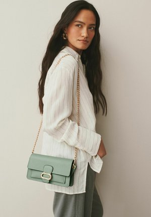 Geantă crossbody din piele verde cu curea din lanț, formă dreptunghiulară, suprafață texturată și detaliu cu închizătoare aurie.