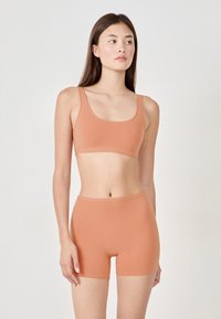 Ljust orange sömlös crop top och shorts-set, med mjukt tyg, en slät textur och en minimalistisk design med breda band och en figurnära siluett.