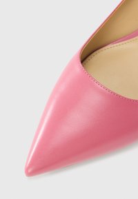 Ροζ δερμάτινη γόβα με μυτερή μυτούλα, λείο φινίρισμα και ελάχιστη ραφή κατά μήκος της άκρης, με εσωτερική επένδυση σε ουδέτερο χρώμα.