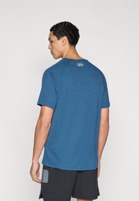 Μπλε αθλητική μπλούζα με κοντά μανίκια, υφασμάτινη με υφή και στρογγυλή λαιμόκοψη. Διαθέτει κυκλικό λογότυπο στην πλάτη.