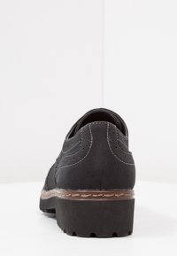 Chaussure en suede noire avec un talon empilé et des accents de couture. Dotée d'un bout rond et d'une semelle texturée pour une bonne adhérence.